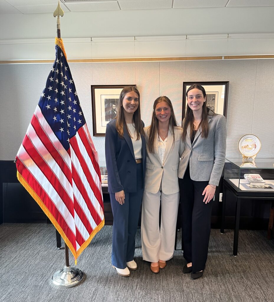 Natalie and 2 other Miami University students standing next to the American flag at the National Defense University