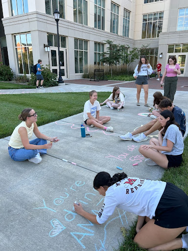 Members writing thoughtful chalk messages during the first meeting of the semester