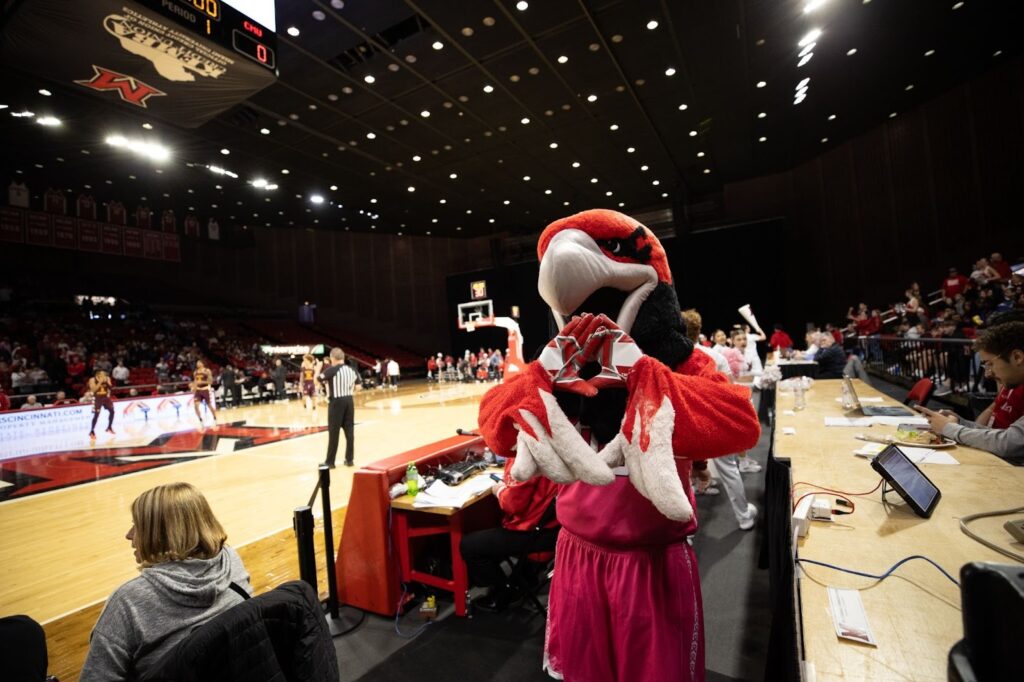Miami University Swoop holding up Miami M at basketball game.