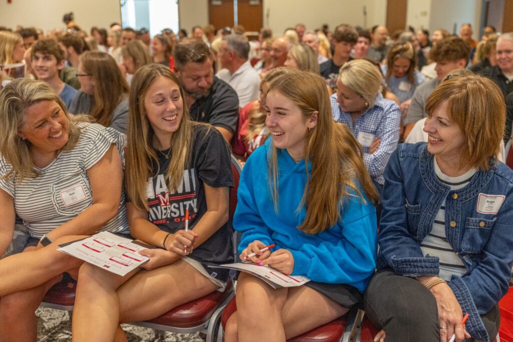 Two incoming Miami University students laughing with their parents at orientation.